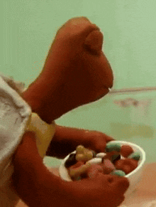 a stuffed animal is holding a bowl of food