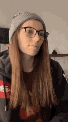 a woman wearing glasses , a beanie , and a north face jacket .