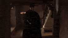 a man in a black cape and mask holds a torch