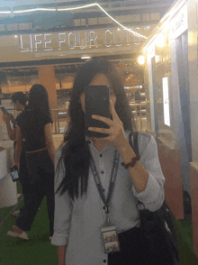 a woman taking a selfie in front of a life four cuts store