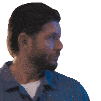 a man with a beard and a blue shirt looks to the side