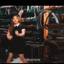 a woman in a black dress is dancing in a room with the name sassymj on the bottom right
