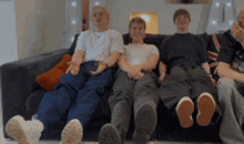 a group of young men are sitting on a couch with their legs crossed