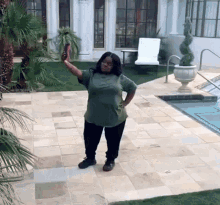 a woman in a green shirt is taking a selfie in front of a swimming pool
