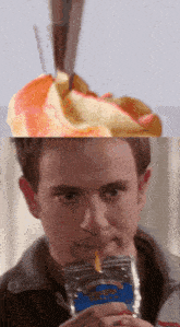 a close up of a man drinking from a bag with a straw next to an apple