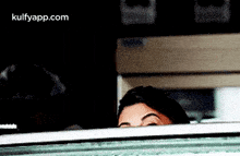 a woman is peeking out from behind a glass door .