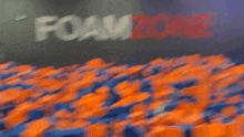 a man is jumping in a pool of foam blocks in front of a sign that says foamzon