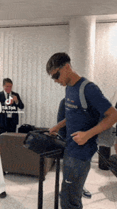 a man wearing sunglasses and a blue shirt that says champions on it