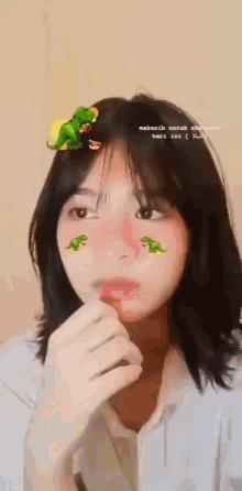 a girl with a dinosaur sticker on her head is eating a candy bar .