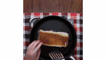 a person is cooking a sandwich in a skillet with a spatula .