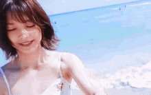 a woman in a white tank top is standing on a beach .