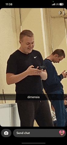 two men are looking at their cell phones and one has dimensia written on his shirt