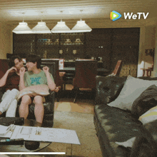 a couple sitting on a couch with the wetv logo in the background