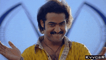a man with a mustache is wearing a yellow shirt with a kvvcsr logo on the bottom