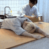 a man is stretching another man 's arms on a kitchen counter