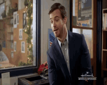 a man in a suit and tie is standing in front of a printer in a hallway .
