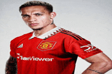 a man wearing a red teamviewer jersey is standing with his hand on his shoulder .