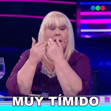 a woman sitting at a table with the word muy timido written in white