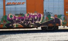 a bnsf train car has graffiti on the side of it