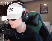 a young man wearing a hat and headphones is sitting in a chair .