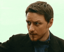 a man with a beard is wearing a black coat