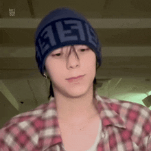 a young man wearing a plaid shirt and a blue hat .