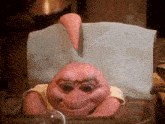 a pink cartoon character is sitting in a chair with a towel around his neck .