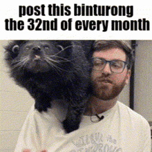a man with glasses is holding a black cat on his shoulder .