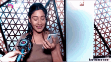 a woman is talking into a microphone with kutumotox written on the bottom of the screen