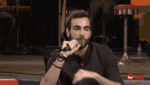 a man singing into a microphone with rai radio 2 on the bottom