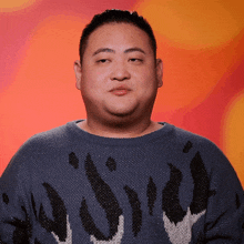 a man wearing a blue sweater with flames on it looks serious