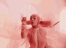 a woman in a pink dress is dancing in front of a pink wall