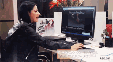 a woman sits at a desk with a computer and a sign that says como no te quiero