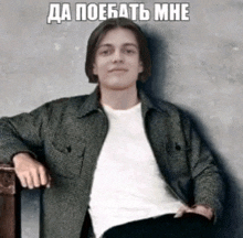 a man in a plaid jacket is sitting in a chair with his hands on his knees and a caption in russian