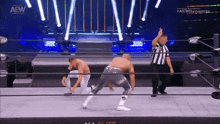 two men are in a wrestling ring with a referee and a sign that says aew dynamite