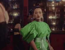 a woman in a green dress stands in front of a bar that says ' jägermeister ' on it