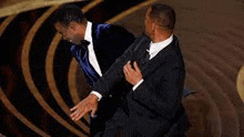 two men in suits and bow ties are standing next to each other on a stage at an awards show .