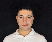 a man wearing a white shirt looks at the camera