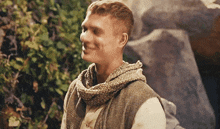 a man wearing a scarf around his neck looks to his left