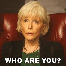 a woman with blonde hair is sitting in a red chair with the words who are you behind her