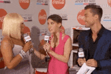 a woman in a pink dress is being interviewed by two men