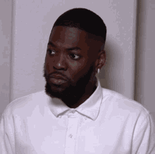 a man with a beard wearing a white shirt and earrings