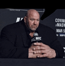 a man in a suit holds a microphone that says ufc on it
