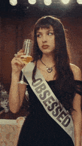 a woman wearing a sash that says obsessed