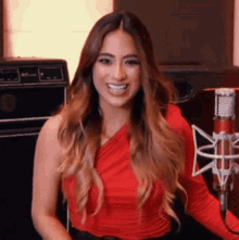 a woman in a red top stands in front of a microphone