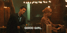 a man and a woman are standing in a dark room with the words good girl written on the screen