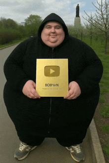 a fat man in a black hoodie is holding a youtube gold award