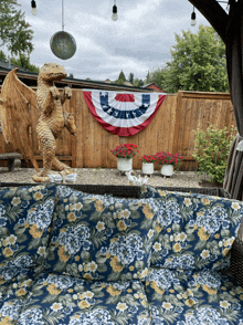 a statue of a dragon is sitting on a couch in front of an american flag