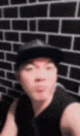 a blurry picture of a man wearing a hat and a tank top in front of a brick wall .