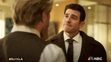 a man in a suit and tie is talking to another man with #suitsla written on the bottom